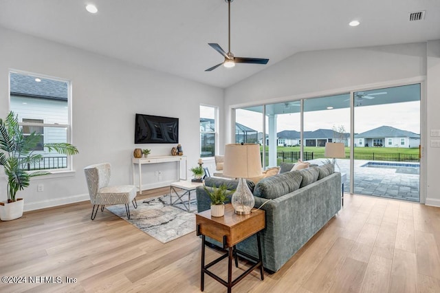 living room with ceiling fan, light hardwood / wood-style floors, and vaulted ceiling