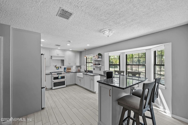 kitchen featuring backsplash, range with two ovens, a breakfast bar area, light hardwood / wood-style floors, and a textured ceiling