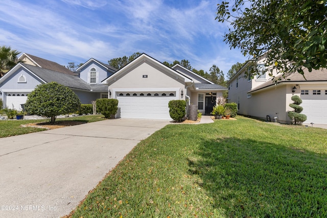 single story home with an attached garage, concrete driveway, a front yard, and stucco siding