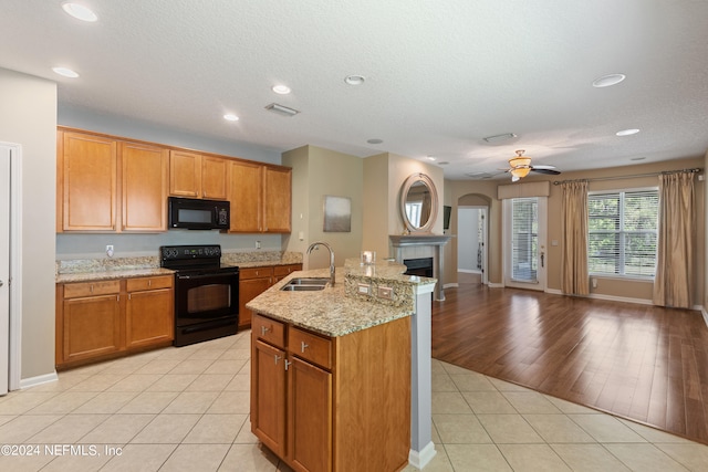 kitchen featuring open floor plan, a sink, black appliances, and light tile patterned floors