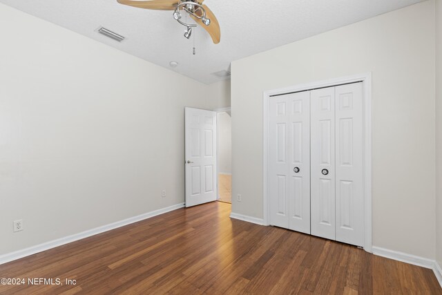 unfurnished bedroom featuring a closet, visible vents, ceiling fan, wood finished floors, and baseboards