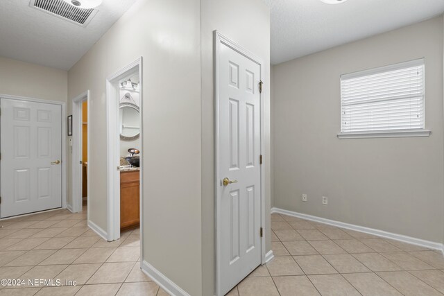 hall with baseboards, visible vents, and light tile patterned flooring