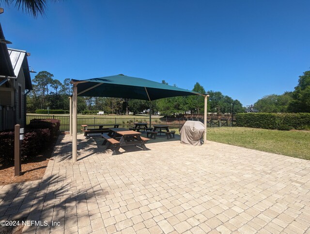 view of patio with fence and a grill