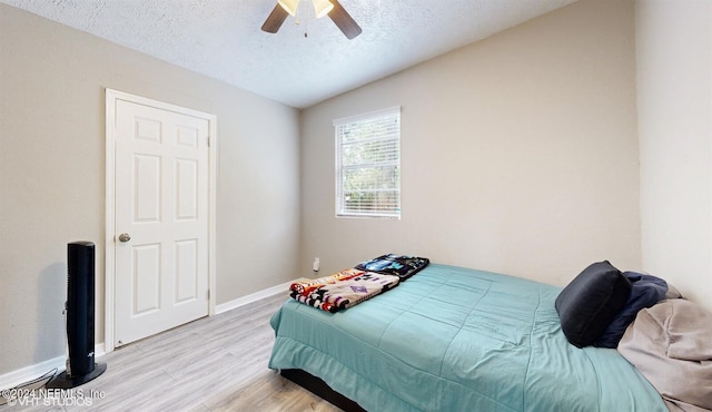 bedroom with lofted ceiling, ceiling fan, light wood-type flooring, and a textured ceiling