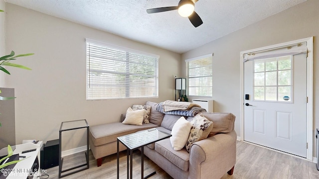 living room featuring a textured ceiling, ceiling fan, light hardwood / wood-style floors, and vaulted ceiling