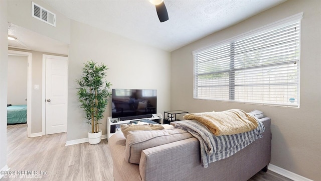 living room with vaulted ceiling, ceiling fan, a textured ceiling, and light wood-type flooring