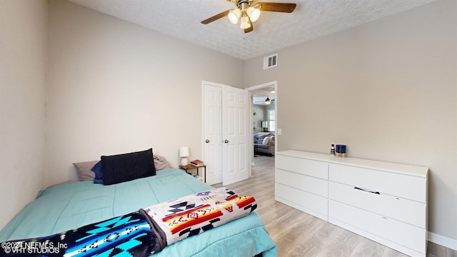 bedroom featuring ceiling fan, light wood-type flooring, and a textured ceiling