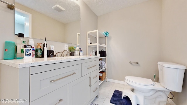 bathroom with vanity with extensive cabinet space, toilet, tile floors, and a textured ceiling