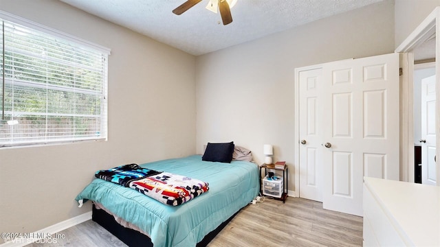 bedroom with a textured ceiling, ceiling fan, and light hardwood / wood-style floors