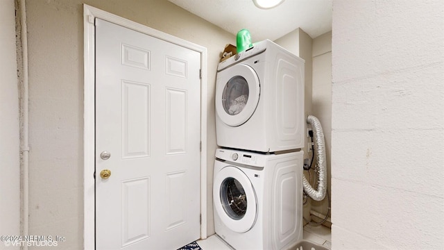 clothes washing area featuring light tile floors and stacked washer / drying machine