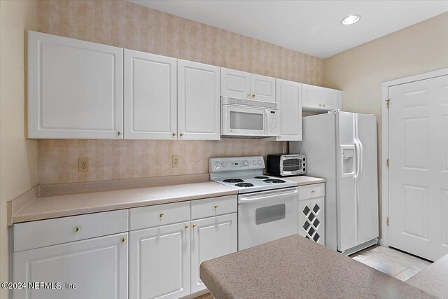 kitchen featuring white cabinets, white appliances, and light tile flooring