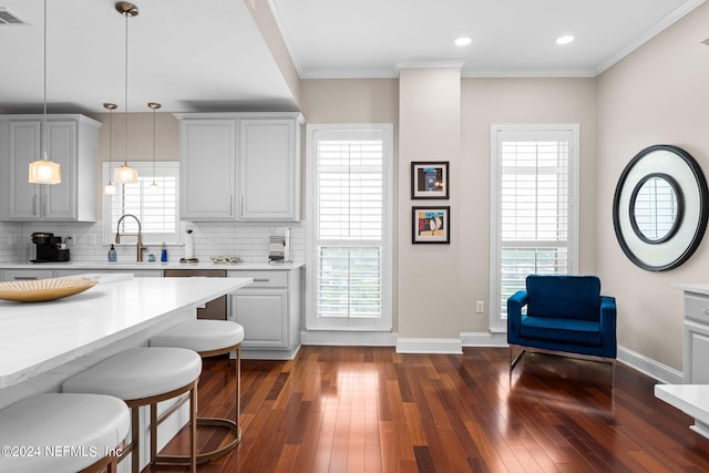 kitchen with decorative light fixtures, a kitchen bar, tasteful backsplash, and dark wood-type flooring