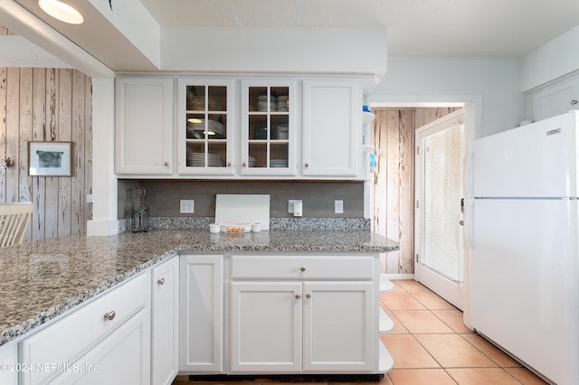 kitchen featuring white refrigerator, a healthy amount of sunlight, white cabinets, and light stone counters