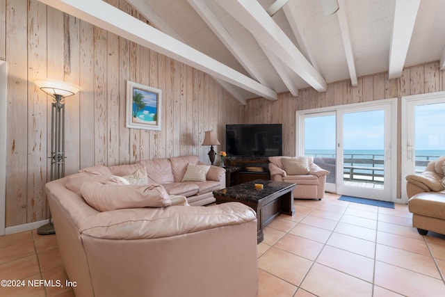 tiled living room featuring wood walls, lofted ceiling with beams, and a water view