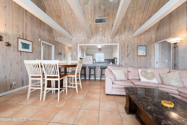 interior space featuring wooden walls, beam ceiling, high vaulted ceiling, and light tile flooring