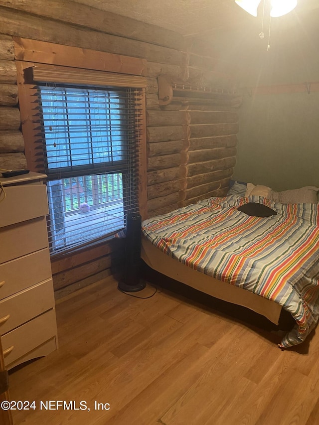 bedroom with hardwood / wood-style flooring and rustic walls