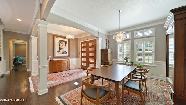 dining room with crown molding, dark hardwood / wood-style floors, ornate columns, a textured ceiling, and an inviting chandelier