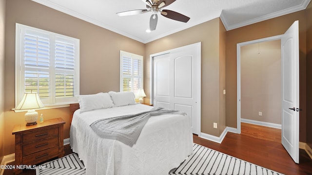 bedroom featuring a closet, ceiling fan, crown molding, and dark wood-type flooring