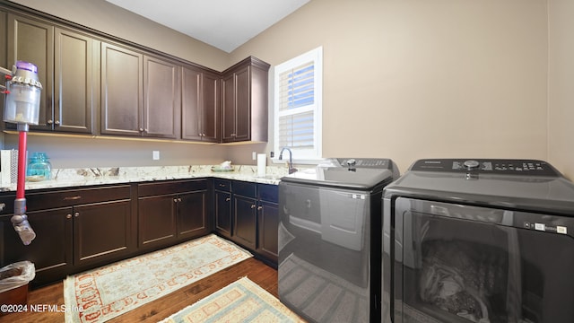 laundry area featuring cabinets, sink, dark hardwood / wood-style flooring, and washer and clothes dryer