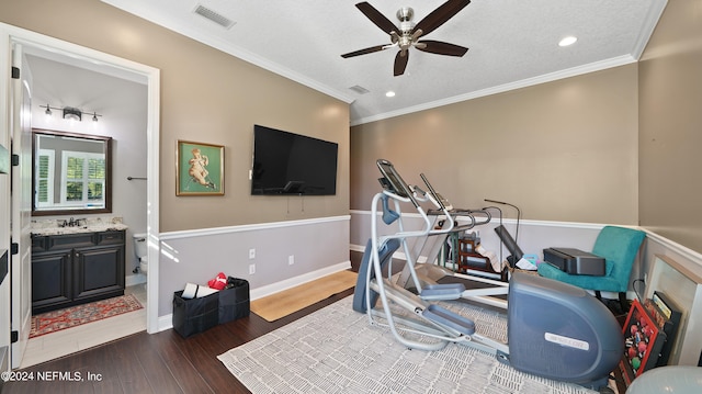 workout room with sink, ceiling fan, crown molding, and dark wood-type flooring