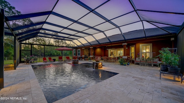 pool at dusk featuring pool water feature, a lanai, and a patio