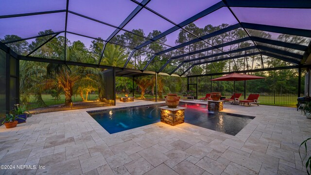 pool at dusk with a patio area, pool water feature, a fire pit, and a lanai