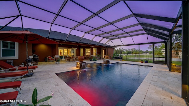 pool at dusk with a lanai, pool water feature, and a patio area