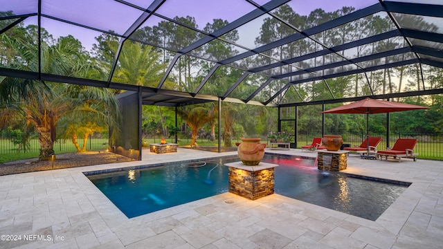 pool at dusk featuring a lanai, an outdoor fire pit, and a patio area