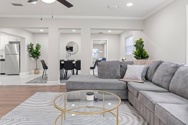 tiled living room with crown molding and ceiling fan