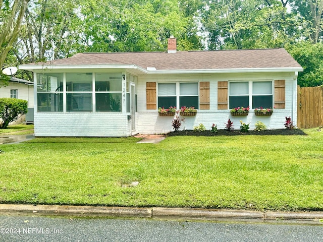 view of front of home featuring a front yard and a sunroom