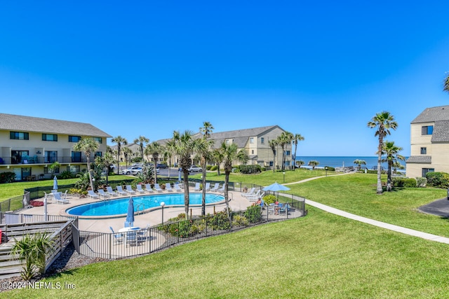 view of swimming pool with a yard and a water view