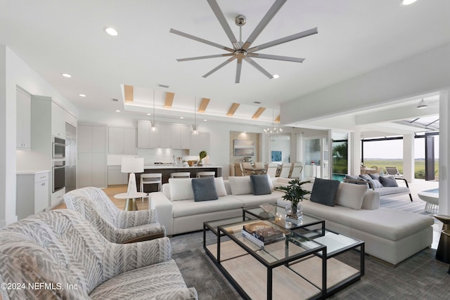 living room with ceiling fan, a raised ceiling, and dark hardwood / wood-style floors