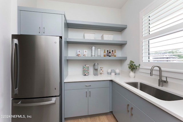 kitchen with light hardwood / wood-style floors, stainless steel refrigerator, sink, and gray cabinets