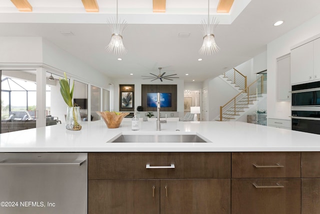 kitchen with white cabinets, hanging light fixtures, sink, and stainless steel dishwasher