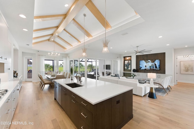 kitchen featuring white cabinets, sink, an island with sink, and light wood-type flooring