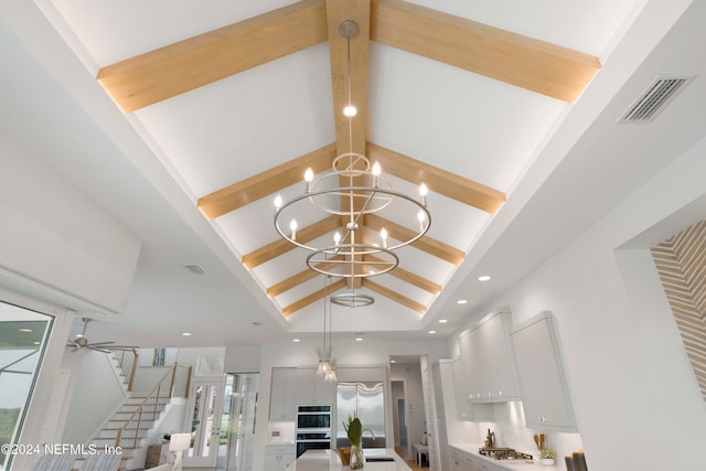 interior details with beamed ceiling, stainless steel refrigerator, ceiling fan with notable chandelier, double oven, and sink