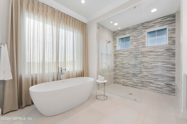 bathroom featuring a healthy amount of sunlight, tile floors, and plus walk in shower