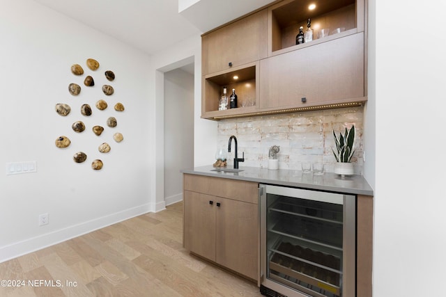 kitchen with beverage cooler, sink, light hardwood / wood-style flooring, and backsplash