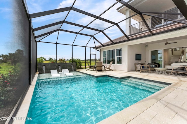 view of swimming pool featuring glass enclosure, a patio area, pool water feature, ceiling fan, and an outdoor hangout area