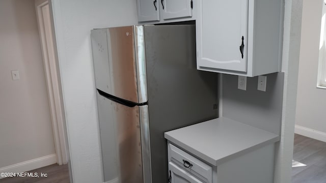 kitchen featuring white cabinetry, wood-type flooring, and stainless steel fridge