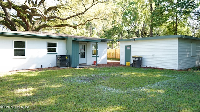 rear view of property featuring central AC unit and a lawn