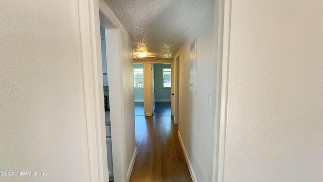 hallway with dark hardwood / wood-style floors and a textured ceiling