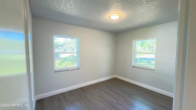 empty room featuring a textured ceiling and dark wood-type flooring