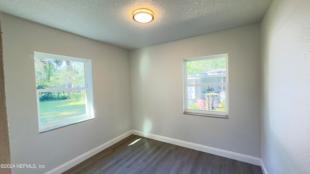 unfurnished room with a textured ceiling and dark wood-type flooring