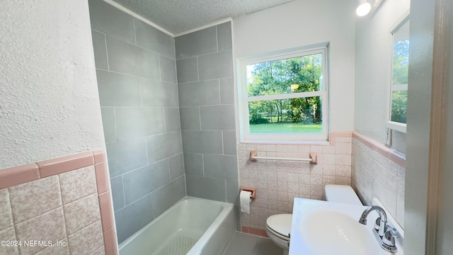 full bathroom featuring tile walls, a textured ceiling, sink, and toilet