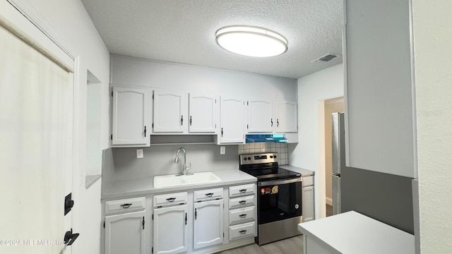 kitchen featuring white cabinets, backsplash, appliances with stainless steel finishes, sink, and a textured ceiling