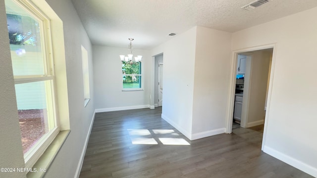 unfurnished room featuring dark hardwood / wood-style floors, a notable chandelier, and a textured ceiling