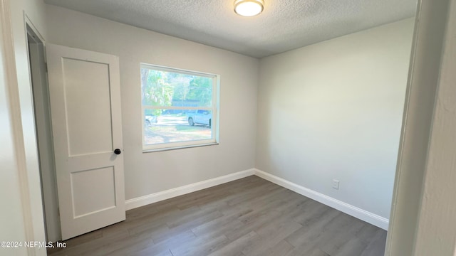 unfurnished room featuring a textured ceiling and light hardwood / wood-style floors