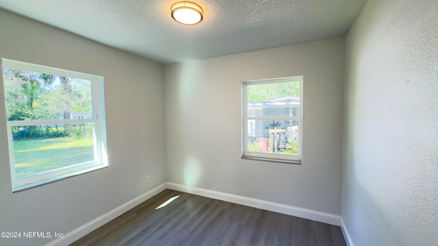 empty room featuring a textured ceiling and dark wood-type flooring