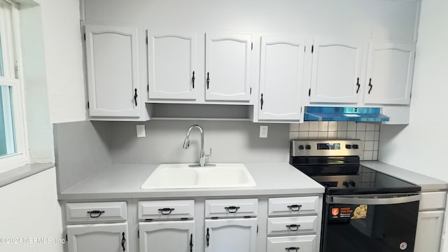 kitchen featuring fume extractor, sink, stainless steel electric stove, and white cabinetry